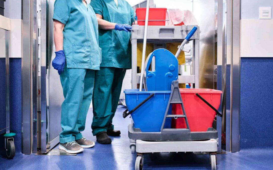 cleaning staff next to a cleaning cart at a hospital